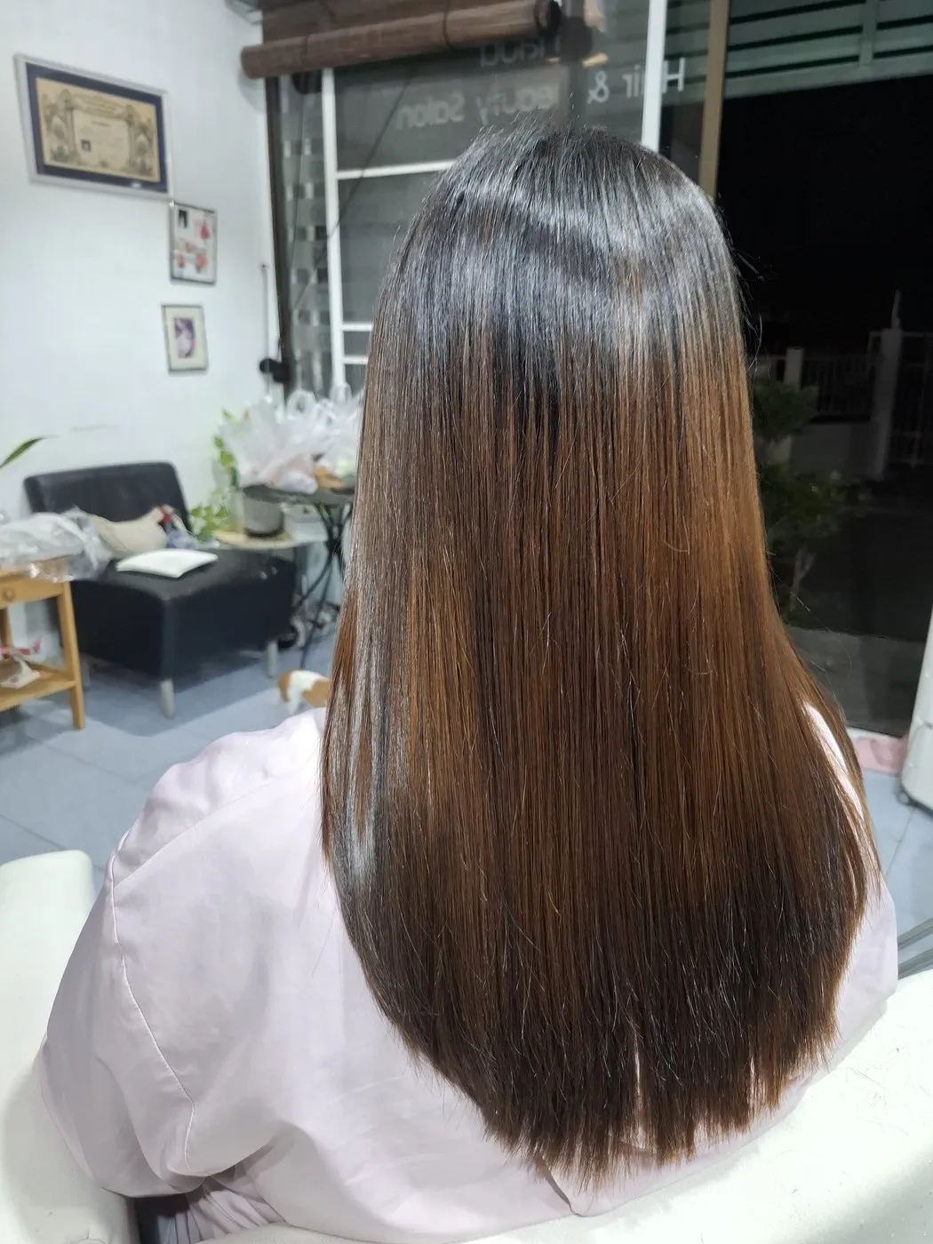 Long straight hair, darker at the roots and lighter brown at the ends, seen from behind